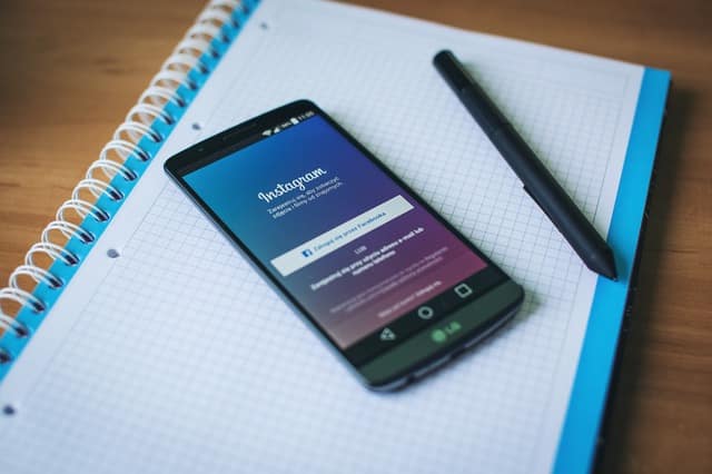 Phone displaying Instagram sitting on top of a notepad